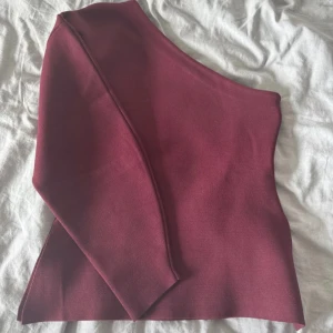 Vinröd oneshoulder topp - Snygg vinröd oneshoulder topp med en stilren design. Perfekt för att ge en trendig touch till din outfit. Passar bra till både jeans och kjol. Finns ej kvar längre, använd en gång!