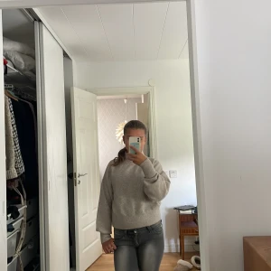 Beige stickad polotröja - Mysig beige stickad polotröja med ribbad hög krage och långa ärmar. Tröjan har en relaxed passform och är perfekt för kyliga dagar. Enkel att matcha med jeans eller kjol för en chill look.