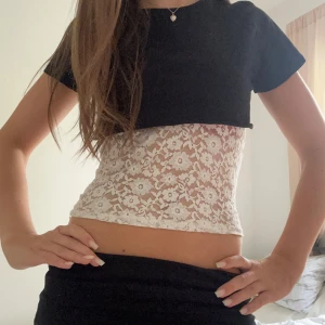 Vit spetsig linnetopp med blommönster - Supersöt croppad linnetopp i vit spets med blommigt mönster. Toppen är ärmlös med tunna axelband och har en transparent look som ger en trendig vibe. Perfekt att styla lager på lager eller bära som den är för en cool och feminin stil.