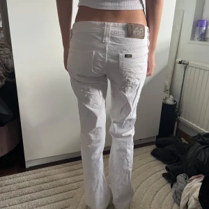 Vita Lee jeans med låg midja - Säljer ett par fräscha vita jeans från Lee med låg midja och bootcut. Jeansen har klassiska fem fickor, silverfärgade detaljer och Lee-logga bak på linningen. Perfekta för en clean och stilren look. Materialet känns mjukt och bekvämt. Nya utan prislapp