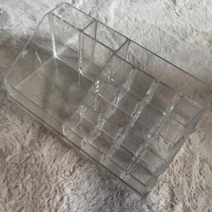 sminkorganiserare  - Snygg och praktisk sminkorganiserare i genomskinlig akryl med flera fack i olika storlekar. Perfekt för att hålla ordning på läppstift, läppglans, ögonbrynspennor och sminkborstar. Stilren design som passar på alla sminkbord.