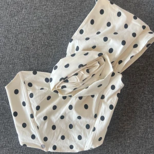 Prickig one shoulder topp från Zara - Supersnygg vit one shoulder topp från Zara med svarta prickar och en stor tygros på framsidan. 🤍🖤