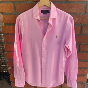 Ralph Lauren Skjorta Rosa - Säljer denna rosa Ralph Lauren skjorta i mycket bra skick. Perfekt på sommarn men funkar lika bra resten av året. Nypris ligger på omkring 1500kr. Hör av er vid frågor eller funderingar. Priset kan diskuteras