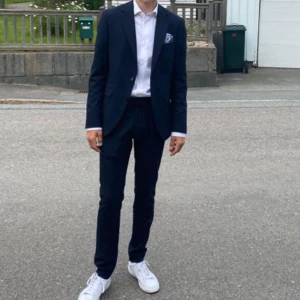 Mörkblå kostym med kavaj och byxor - Snygg mörkblå kostym med klassisk kavaj och matchande byxor. Kostymen är från märket Riley. Nypris 3000kr. Som ny, använd endast ett fåtal gånger. 