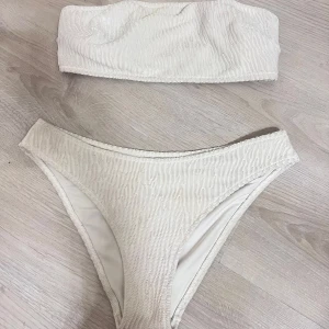 Vit bandeau bikini med struktur - Snygg vit bikini med bandeau-topp och matchande trosor. Bikinin är i storlek 46 men sitter som Xl.