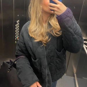 Svart quiltad jacka från Zara - Quiltad svart jacka från Zara med oversized passform och stora fickor framtill. Jackan har dragkedja hela vägen upp, hög krage och coola vågformade sömmar. 