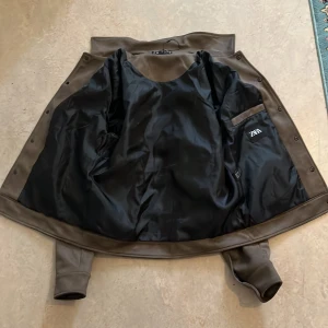 Brun mockajacka från Zara, M - Snygg brun mockajacka från Zara i klassisk jeansjacke-modell. Jackan har två bröstfickor med lock och knappar, samt två sidofickor. Stängs med tryckknappar framtill och har en stilren krage. Perfekt för dig som vill ha en clean och tidlös look.