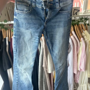 Blå jeans med fickdetaljer bak - Snygga blå jeans med slitningar och coola fickor med lock och knapp bak. Klassisk femficksmodell, dragkedja och knapp framtill Jensen  är tillverkade i jeansmaterial. Perfekta för en avslappnad och trendig look.