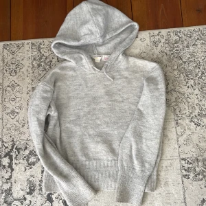 Grå hoodie från Gina Tricot - Passar bra på Ming som har s/xs Mysig grå hoodie från Gina Tricot med huva och långa ärmar. Tröjan har ribbade muddar vid ärmslut och nederkant, perfekt för kyliga dagar. Enkel och stilren design som passar till det mesta.