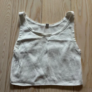 Vit ribbad linnetopp XS - vit ribbad linnetopp från Uniqlo i storlek XS. Toppen är ärmlös med rund halsringning och croppad passform. Använd några fåtal gånger och i bra skick.
