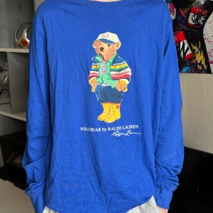 Blå långärmad Polo Bear-tröja XL - Snygg blå långärmad tröja från Polo Ralph Lauren med ikoniska Polo Bear-trycket på bröstet. Tröjan har rund hals och är gjord i mjuk bomull. Använd 5 gånger, nyskick utan prislapp. Nypris: 795kr, Mitt pris: 399kr