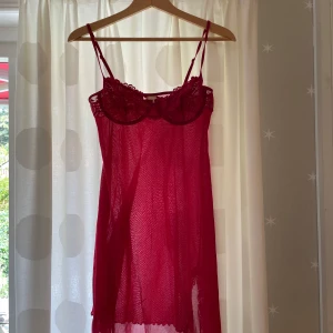 Röd spetsklänning Body Zone KappAhl - Snygg röd kortklänning från Body Zone by KappAhl med tunna axelband och spetsdetaljer upptill och nertill. Klänningen är genomskinlig och har en feminin, romantisk vibe med vackra spetsmönster. Perfekt för dig som vill sticka ut.