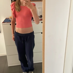 Rosa croppad topp med volangärm Zara - Supersöt croppad topp från Zara i ribbad bomull. Färgen är en härlig rosa och toppen har korta ärmar med volangdetaljer som ger en extra touch. Perfekt till jeans eller kjol för en trendig look. Rund halsringning och figurnära passform.