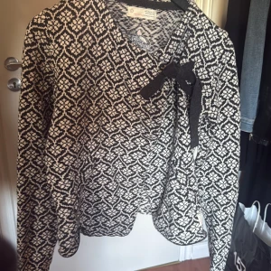 Mönstrad kofta Odd Molly - Svart och vit stickad kofta från Odd Molly med snyggt grafiskt mönster och knytband vid halsen. Långärmad modell med broderad Odd Molly-logga på ryggen. Perfekt för dig som gillar unika detaljer och skön stil. Hittade ingen storlek men passar mig som är S och passar XS också. Säljer eftersom den inte kommer till användning🩷