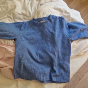 Blå stickad tröja från ONLY - Säljer en ljusblå stickad tröja från ONLY i storlek XS. Tröjan har puffade korta ärmar och ribbade muddar vid hals, ärmslut och nederkant. Perfekt för dig som gillar en enkel men ändå söt look. Superfin färg och skön passform💕 ser helt ny ut använt ett fåtal gånger💘 skriv för frågor och mer bilder❤️