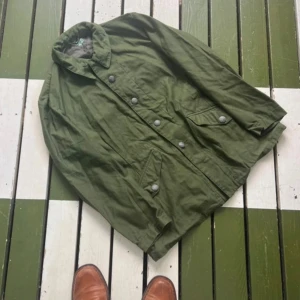  m/59 jacka  Svensk armé 1968 Sällsynt vintage - Otroligt fin och sällsynt original m/59 jacka från svenska armén, daterad 1968 – ett riktigt samlarobjekt och en ikon inom skandinavisk militärhistoria.  Modellen m/59 togs fram för svenska försvaret under kalla kriget och är känd för sin slitstyrka, funktionalitet och klassiska design. Den här varianten är från den senare produktionen, med förbättrat tyg och passform, vilket gör den extra eftertraktad både bland samlare och modeintresserade.  Jackan är i perfekt skick för sin ålder