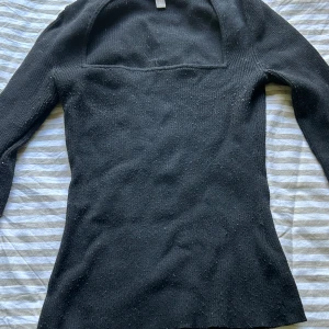 Svart ribbad tröja - Svart stickad tröja från H&M/Monki i storlek M. Tröjan har ribbad struktur, lång ärm och en snygg fyrkantig ringning. Slitsdetalj vid ärmslutet och har inga defekter🫶🏻
