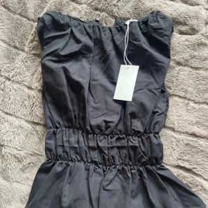 Svart ärmlös knlud med markerad midja - Supersnygg svart blus från NA-KD i storlek 32. Plagget är helt nytt och prislapp sitter kvar!