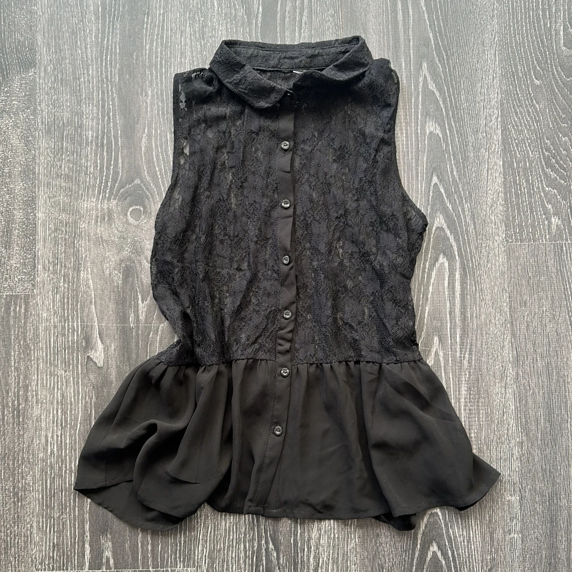 Svart ärmlös blus med spets och volang