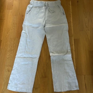  linnebyxor med snörning - Snygga ljusgrå linnebyxor med avslappnad passform och resår i midjan. Byxorna har snörning i midjan och praktiska sidfickor.