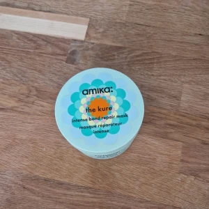 Amika The Kure hårmask 250ml - Amika The Kure intense bond repair mask i en mintgrön burk med färgglad blomdesign. Innehåller 250 ml krämig, vit hårmask som stärker och reparerar håret på djupet. Perfekt för dig som vill boosta håret med extra vård och fukt. Sparsamt använd - mycket produkt kvar! 
