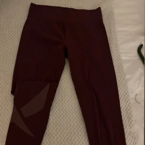 Vinröda leggings med hög midja - Snygga vinröda leggings med hög midja och stretchigt material. Perfekta för träning eller chill, med diskret mönsterdetalj på benet. Sitter tajt och följer kroppen för en sportig look.
