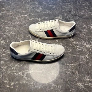 Gucci ace - Säljer ett par otroligt snygga skor från det exklusiva italienska märket Gucci! Skorna är i otroligt bra skick, skulle säga ungefär 8/10. Nypris ligger på över 9000kronor men vi säljer våra för endast 1899 och kan gå ner i pris ännu mer vid snabb affär! Skorna är 41,5 i storlek men stora. Skriv gärna ifall det är några funderingar, allt bästa SkoKapet