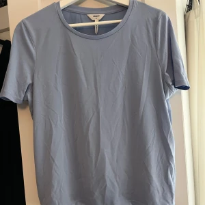 Ljusblå t-shirt från Object - Snygg ljusblå t-shirt från Object i klassisk modell med rund hals och korta ärmar. T-shirten är enkel och stilren, perfekt att matcha med jeans eller shorts. Materialet känns mjukt och skönt mot huden, och färgen är fräsch och somrig.