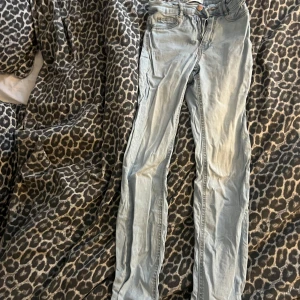 Ljusblå skinny jeans - Säljer ett par ljusblå skinny jeans med klassisk femficksdesign och dragkedja. Jeansen har en smal passform och är perfekta för dig som gillar en tajt look. Materialet är mjukt och stretchigt för extra komfort.