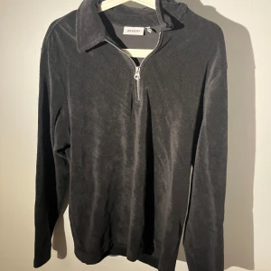 Svart skön tröja Weekday - Svart långärmad tröja från Weekday i mjukt material med halv dragkedja framtill och klassisk krage. Perfekt för dig som gillar chill och stilren vibe. Passformen är normal och materialet känns skönt mot huden. Denna tröja är använd en gång. 