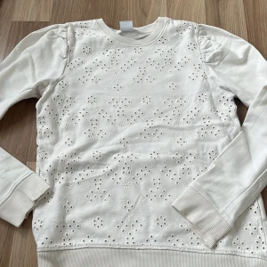 Vit blommig tröja från Zara - Superfin vit tröja från Zara med broderade blommor framtill. Tröjan har rund hals, puffade axlar och långa ärmar med breda muddar. Materialet är mjukt och bomulligt, perfekt för en chill och stilren look.