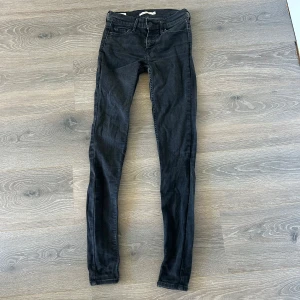 Levi's 710 Super Skinny svarta jeans - Svarta Levi's 710 Super Skinny jeans med tight passform och klassisk femficksdesign. Jeansen har normal midja och är tillverkade i stretchigt denim för en riktigt slimmad look. Perfekta för dig som gillar en smal siluett och stilren vibe.