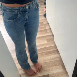 Blå bootcut jeans i storlek 164 - Snygga blå jeans med bootcut passform och klassisk femficksdesign. Jeansen har låg midja och är tillverkade i mjukt denimtyg med lätt tvättad look. Perfekta för dig som gillar en avslappnad men trendig stil.