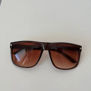 Raybans boyfriend liknande  - Snygga solglasögon med fyrkantig form och brunt plastbåge. Glasen är tonade i brunt och ger en cool vibe till din stil. Perfekta för soliga dagar och ger ett trendigt intryck. Passar dig som gillar klassisk men modern look. Helt nya