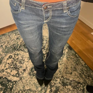 Blå lågmidjade jeans med kontrastsömmar - Säljer ett par blå straight jeans med tydliga vita kontrastsömmar. Jeansen har låg midja och är tillverkade i denim med lätt tvättad look. Perfekta för dig som gillar en avslappnad men ändå snygg stil😝