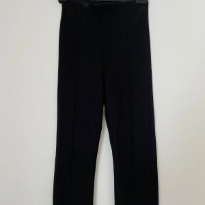 Svarta kostymbyxor från Gina Tricot - Snygga svarta kostymbyxor från Gina Tricot i storlek XXS. Byxorna har hög midja, raka ben och pressveck framtill. Materialet är stretchigt och bekvämt, perfekt för en clean och stilren look.