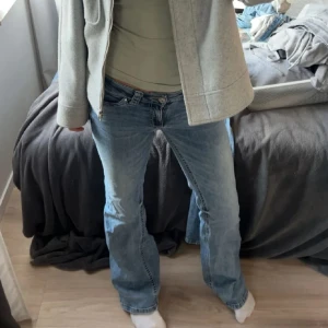 Blå bootcut jeans med slitna detaljer - ett par snygga populära Nelly  jeans med låg midja och coola fickdetaljer bak med knappar och broderi. Jeansen  har använts fåtal gånger och har slitning på ena hälen ( inget som syntes på) utgångspris 500 men är diskuterbart!