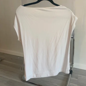 Vit ärmlös linnetopp - En enkel och stilren vit linnetopp med lös passform och ärmlös design. Perfekt för varma dagar och lätt att matcha med olika outfits. Tunt och mjukt material som känns skönt mot huden.