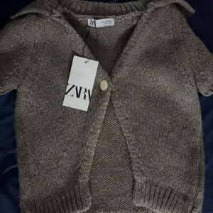 Beige stickad kofta från Zara - Säljer en beige stickad kofta från Zara med korta ärmar och en knapp framtill. helt ny med lappen kvar aldig andväd kontakta vid frågor ny pris 400