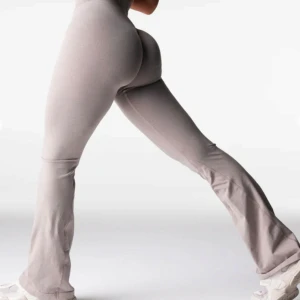 Beige träningstights med bootcut från NVGTN - Säljer ett par beige träningstights från NVGTN med bootcut och hög midja. Tightsen är sömlösa och har en tight passform upptill som övergår i utsvängda ben. Perfekta för gymmet eller vardagslooken.