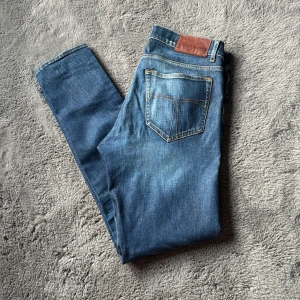 Blå jeans från tiger of Sweden - Säljer ett par klassiska blå jeansbyxor med raka ben och en slim fit. Perfekta till vardags och passar till det mesta. Snygg och tidlös modell. Storlek w32 L32. Pris kan diskuteras vid snabb affär!