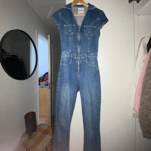 Jeans jumpsuit med dragkedja - Snygg jeans jumpsuit med korta ärmar och dragkedja framtill. Två bröstfickor med lock och liten krage. I storlek xs köpt från bershka, kan bytas mot samma i s. Använd 2 gånger