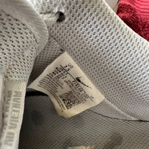 Nike Air Force 1 vita sneakers - Klassiska vita Nike Air Force 1 sneakers med rund tå och platt sula. Skorna har snörning och är tillverkade i skinn med perforerade detaljer på tån för extra ventilation. Swoosh-logga på sidan och diskret branding på plösen.