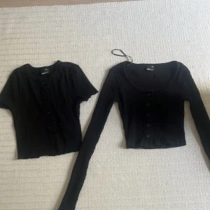 Svarta toppar  - Två svarta croppade koftor från Gina Tricot i ribbat material. En med lång ärm och en med kort ärm, båda med knappar framtill. Perfekta att styla lager på lager eller var för sig.båda ingår💕💕