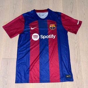 FC Barcelona hemmatröja  - Säljer en officiell FC Barcelona hemmatröja från Nike med klassiska blå och röda ränder. Tröjan har klubbmärke, Nike-logga och Spotify som sponsor på bröstet. Kortärmad modell i Dri-Fit material för bästa komfort. Storlek M.