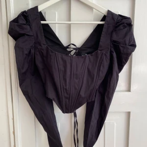 Svart korsettopp med puffärmar från Bershka - Säljer en svart korsettopp från Bershka med puffiga långa ärmar och snörning i ryggen🐦‍⬛