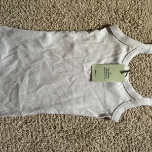 ljusblått linnetopp från Gina Tricot - Säljer en ljusblå ribbad linnetopp från Gina Tricot. Toppen har en klassisk rund halsringning, perfekt för varma dagar eller som lager under andra plagg.