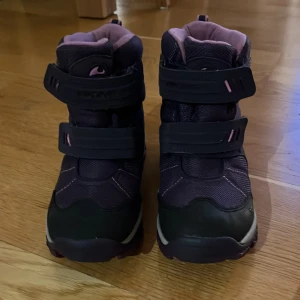 Lila vinterboots från Viking - Säljer ett par lila vinterboots från Viking med rosa detaljer och kardborreband. Skorna har en robust sula och är fodrade för extra värme. Perfekta för kalla dagar och håller fötterna torra och varma, de är i storlek 35 och har används en vinter. Lite smuts här och där men går att torka bort och inga defekter som jag kan se: kontakta vid frågor!💕 Nästan ny skick!