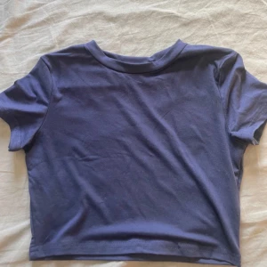 Mörkblå croppad t-shirt - En enkel och stilren mörkblå croppad t-shirt med rund halsringning och korta ärmar. Perfekt för en avslappnad look och lätt att matcha med jeans eller kjol.