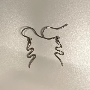 Orm silver örhängen  - Säljer ett par coola silvriga orm örhängen. Perfekta för dig som vill ha något unikt. Passar till alla tillfällen och ger en edgy touch till din look. Äkta silver. 